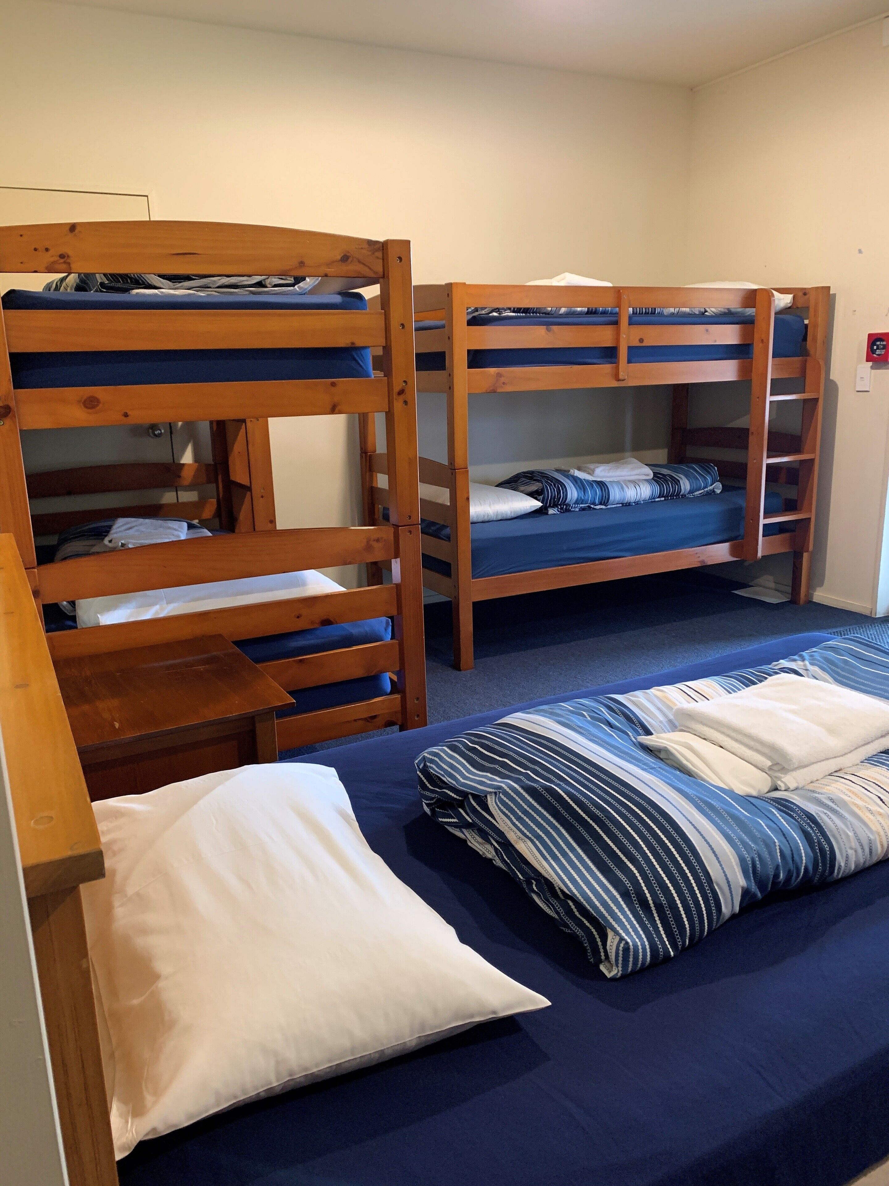 A bunk bed room with wooden frames, a desk, and a bed with striped bedding.