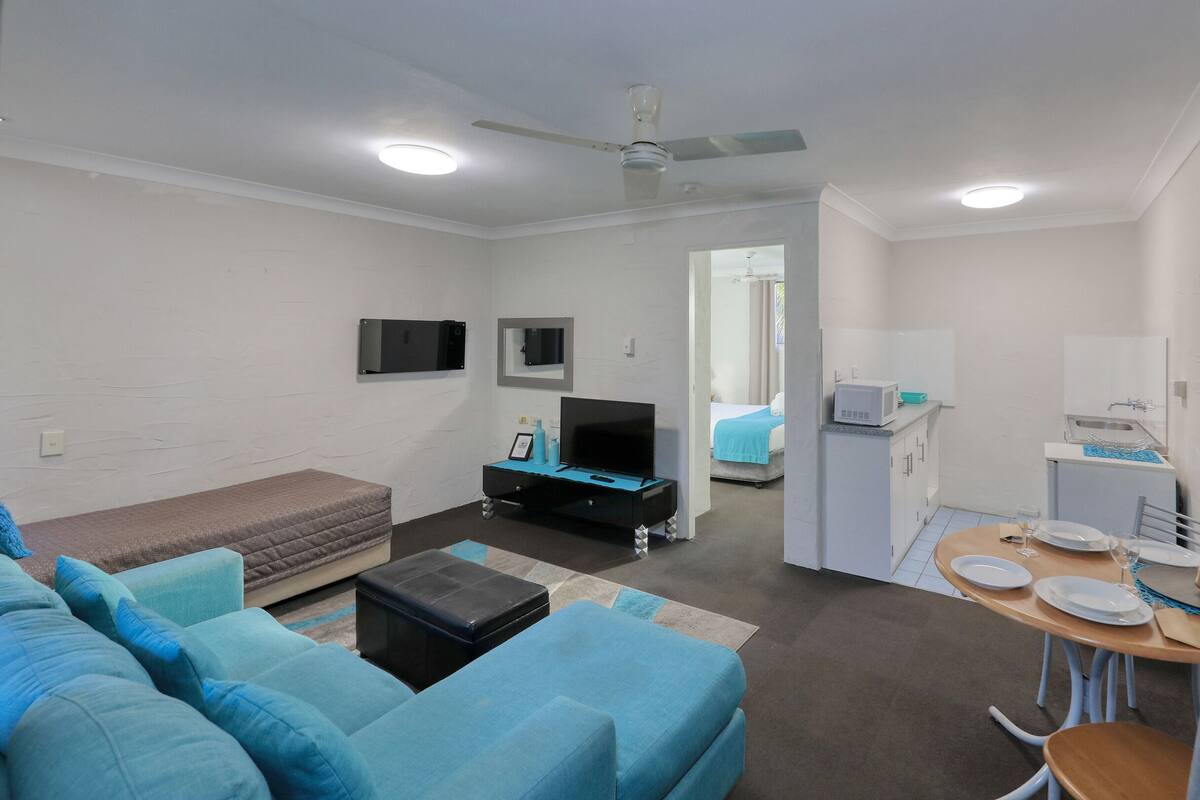 A compact living space with a sofa, a small TV, a kitchenette, and a dining area.