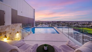 Une piscine sur le toit offrant une vue sur la ville, avec un mur en pierre et un espace détente.