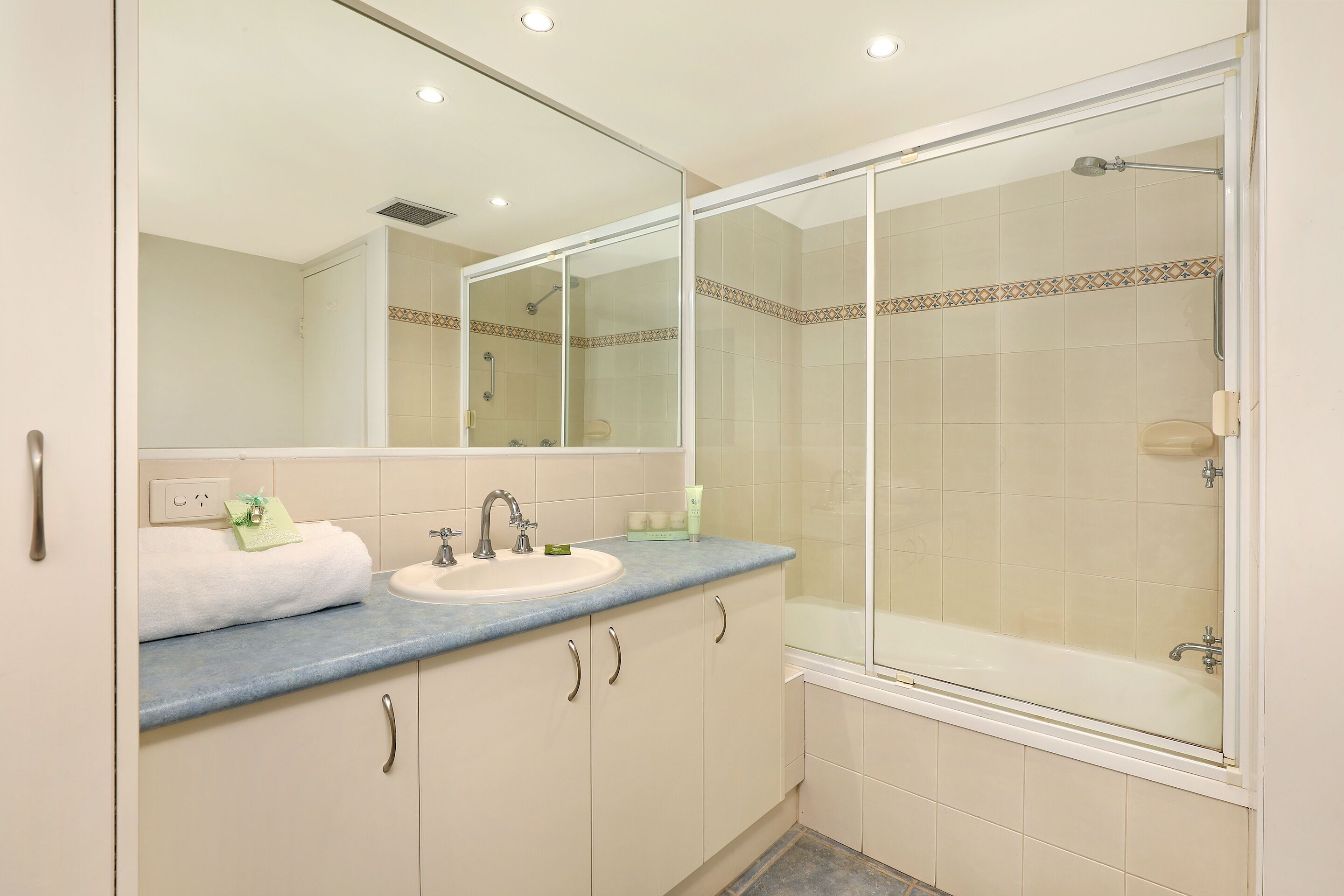 A bathroom with a sink, mirror, and shower.