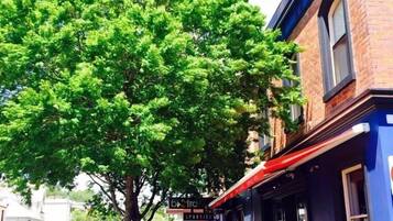 A tree-lined street with a building labeled "SPORTIES HOTEL" featuring outdoor seating.