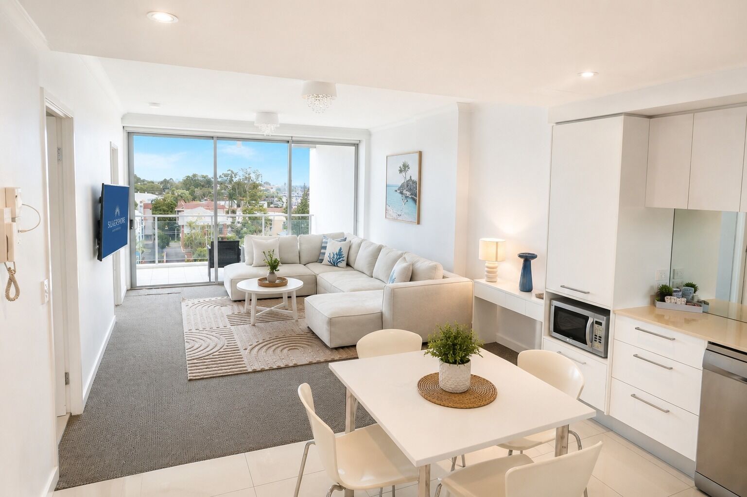 Un appartement moderne comprenant un espace de vie, un coin repas, une cuisine et de grandes fenêtres offrant une vue sur la ville.