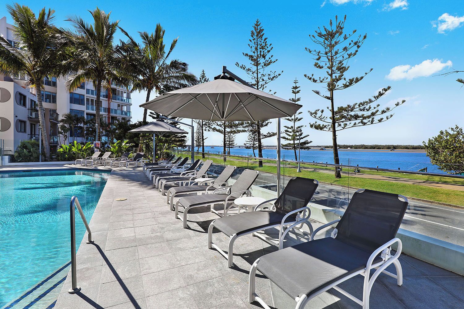 A poolside area with lounge chairs and umbrellas, overlooking a body of water.