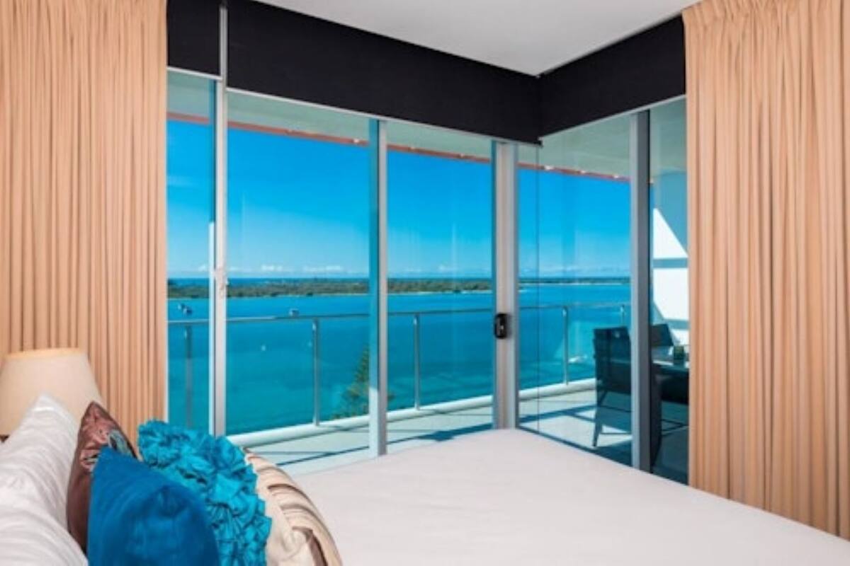 Ein Hotelzimmer mit einer großen Schiebeglasdoor, die auf einen Balkon mit Meerblick führt.
