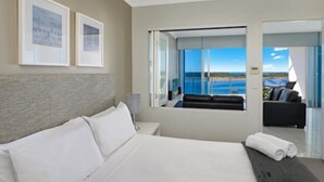 Une chambre d’hôtel moderne dotée d’un grand lit, d’une vue sur la mer et d’un balcon avec un canapé.