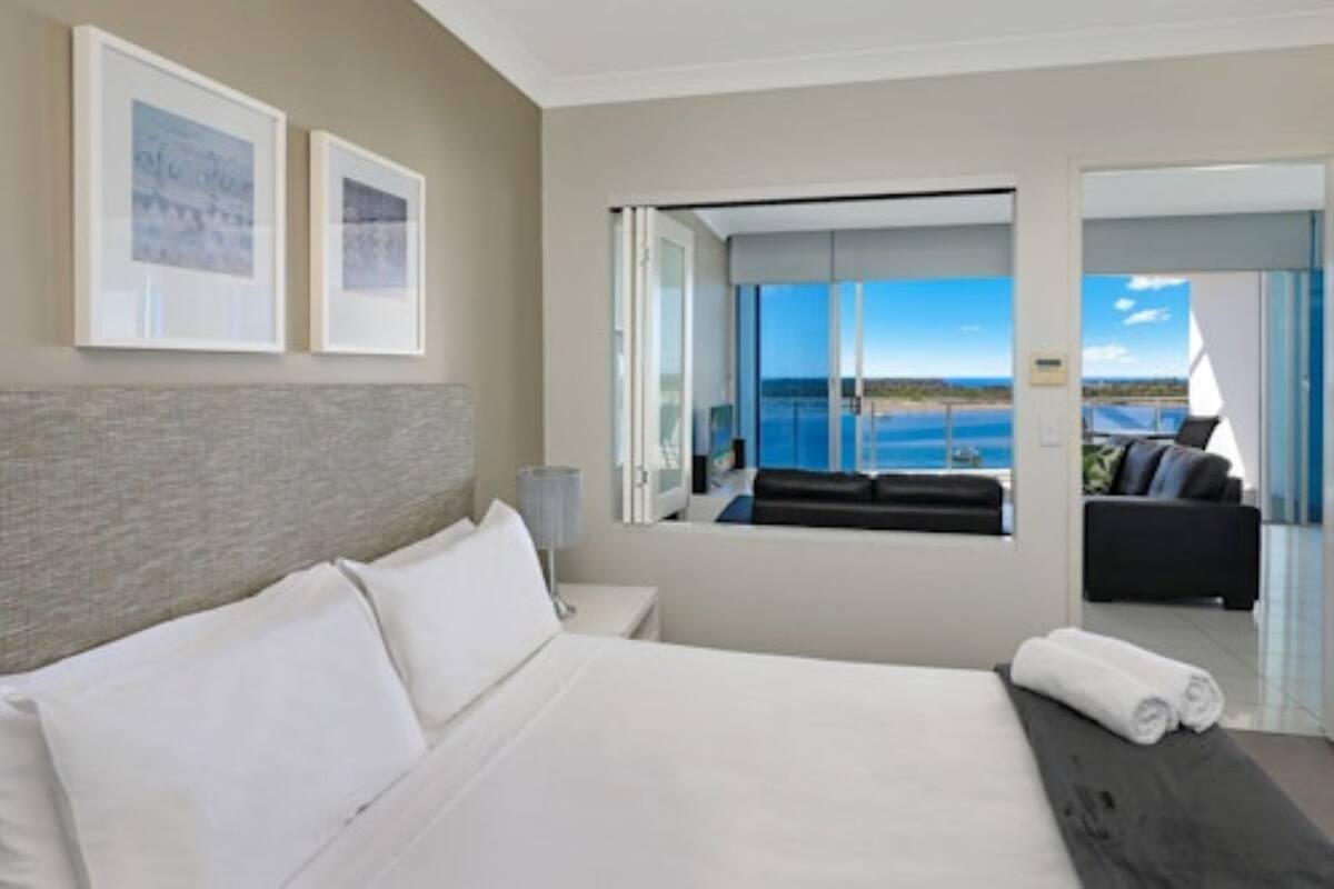 Ein modernes Hotelzimmer mit einem großen Bett, Meerblick und einem Balkon mit einer Couch.