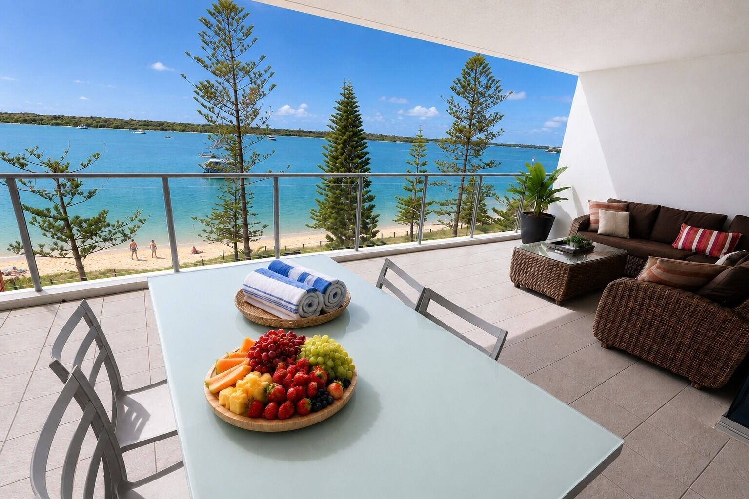 Un balcón con una mesa lista para comer, un sofá y vistas a la playa y al mar.