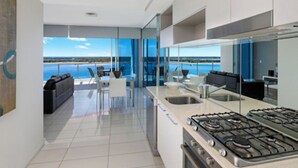 Une cuisine moderne avec vue sur l’océan, un coin repas avec une table et des chaises, et une grande fenêtre.