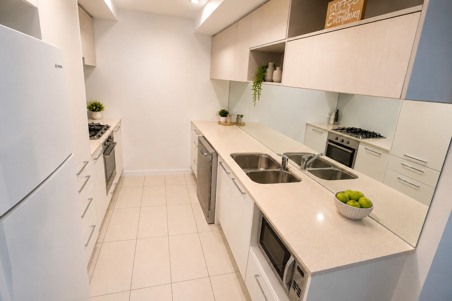 A modern kitchen with white cabinetry, stainless steel appliances, and a bowl of green apples on the counter.