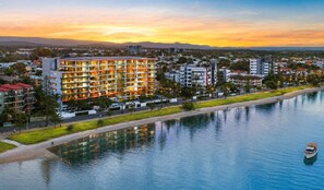 A hotel with multiple floors, a waterfront view, and a body of water in the foreground. - Silvershore Apartments on the Broadwater (Biggera Waters)