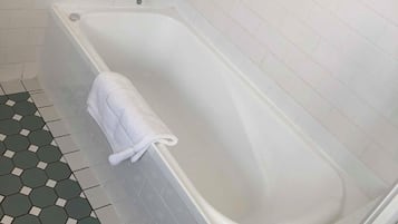 Un baño con una bañera blanca, una toalla y un suelo de baldosas hexagonales.