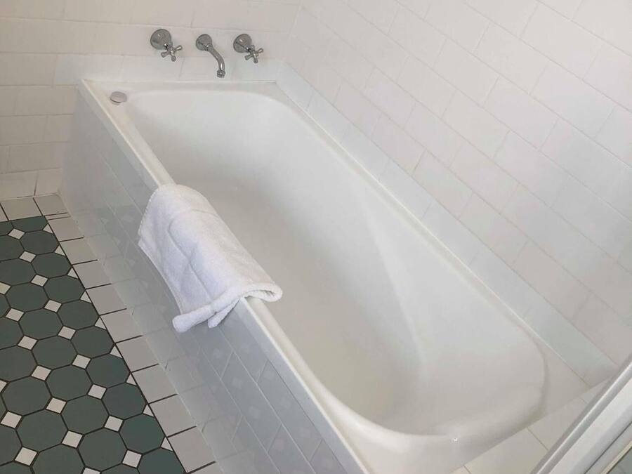 Un baño con una bañera blanca, una toalla y un suelo de baldosas hexagonales.