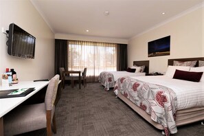 A hotel room with two beds, a desk, a chair, a TV, and a window with curtains. - Young Federation Motor Inn (Young)