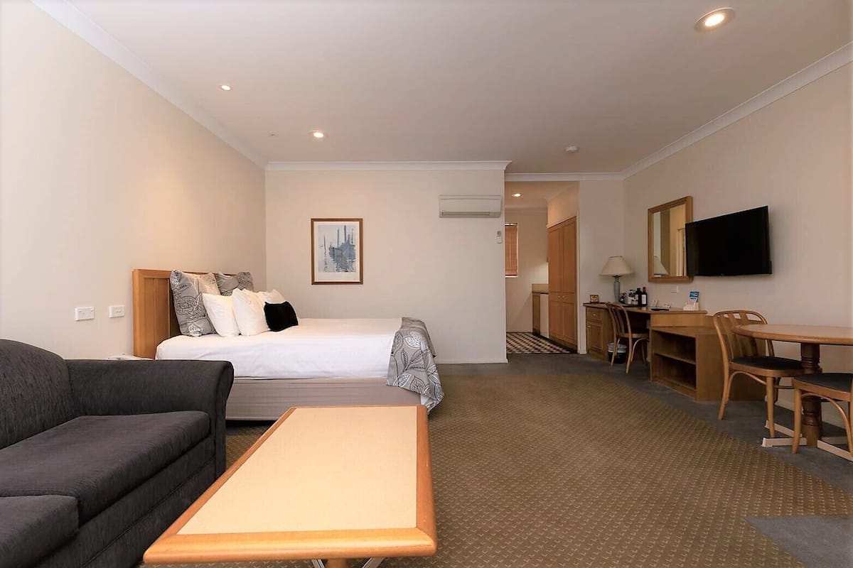 Une chambre d’hôtel comprenant un lit, un canapé, un bureau, une chaise et un téléviseur.