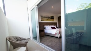 A bedroom with a bed, a nightstand, a chair, and a sliding glass door leading to a balcony. - Young Federation Motor Inn (Young)