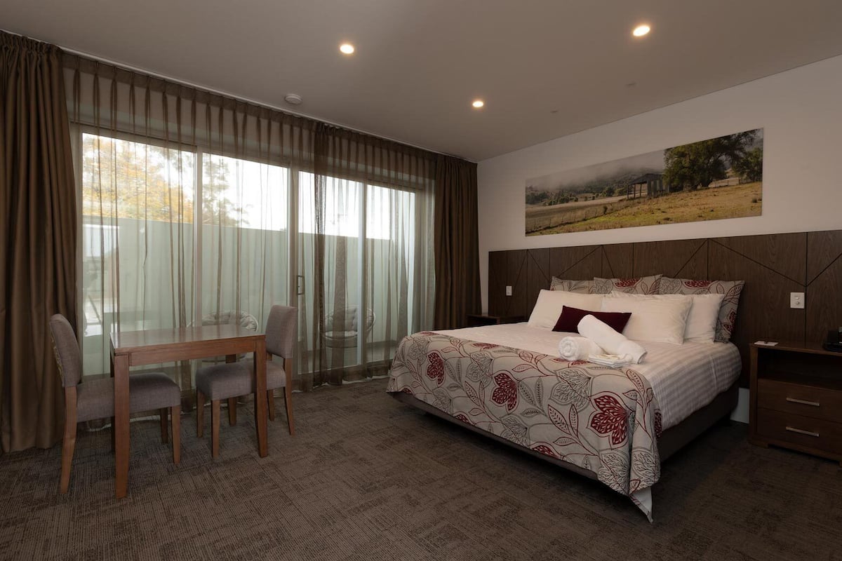 Une chambre d’hôtel avec un grand lit, une table à manger avec des chaises et un tableau au mur.