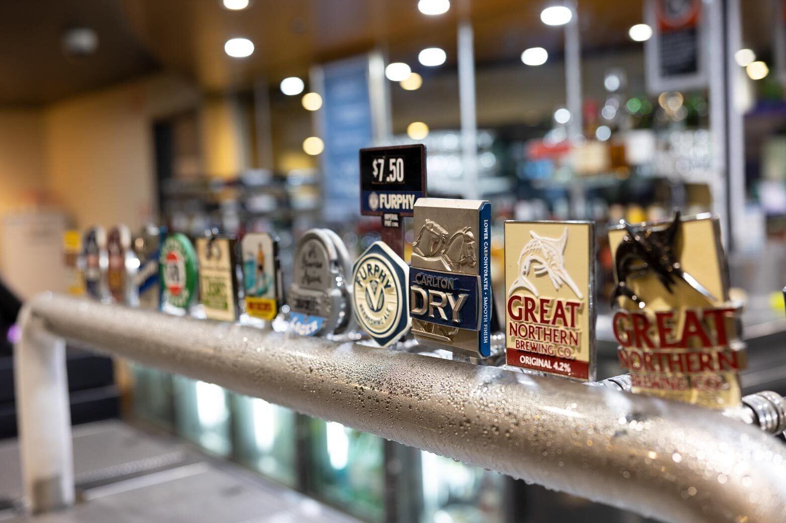 Un bar proposant une variété de bières à la pression, notamment des marques comme Carlton Dry et Great Northern Brewing Co.