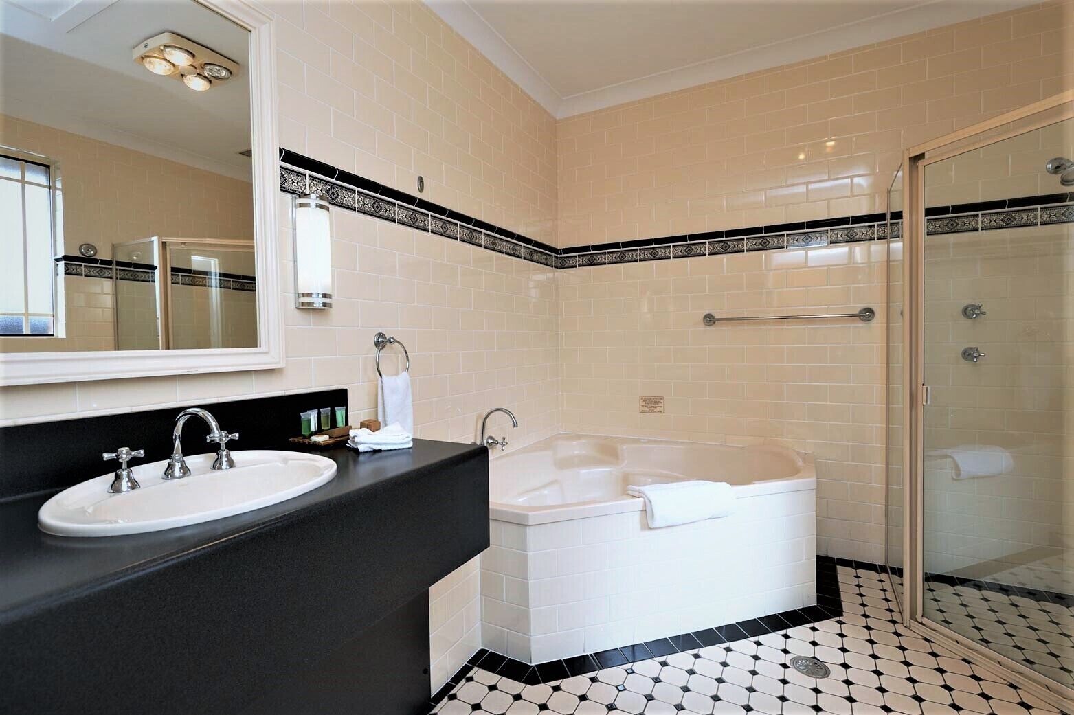 Ein modernes Badezimmer mit schwarzem Waschtisch, einer weißen Badewanne und einer Duschkabine aus Glas.