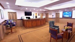 A reception area with a wooden reception desk, a television, and a seating area with chairs and a table. - Young Federation Motor Inn (Young)