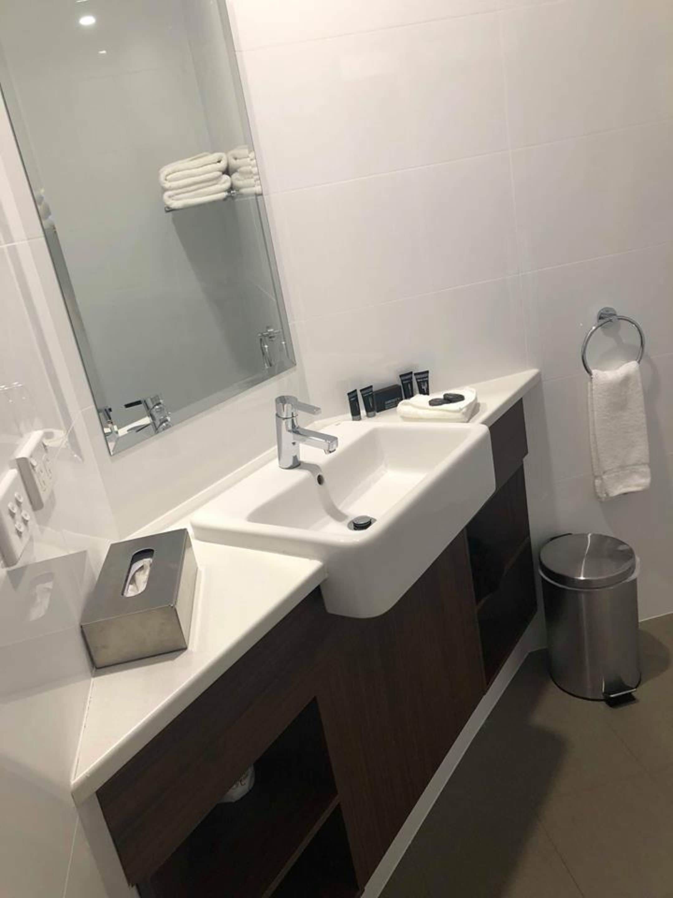 A modern bathroom with a double sink, a large mirror, and a towel rack.
