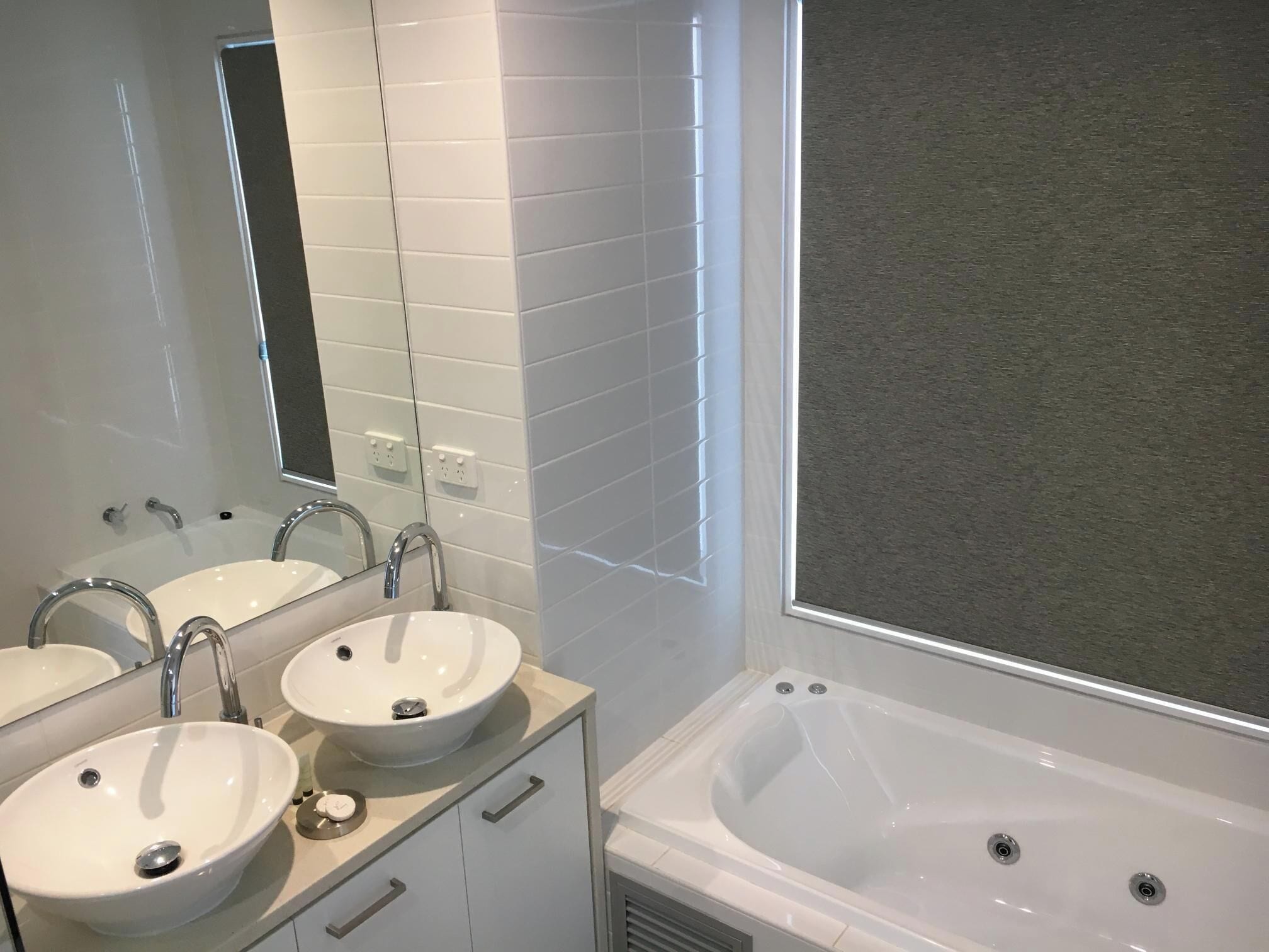 A bathroom with two sinks, a mirror, and a bathtub.