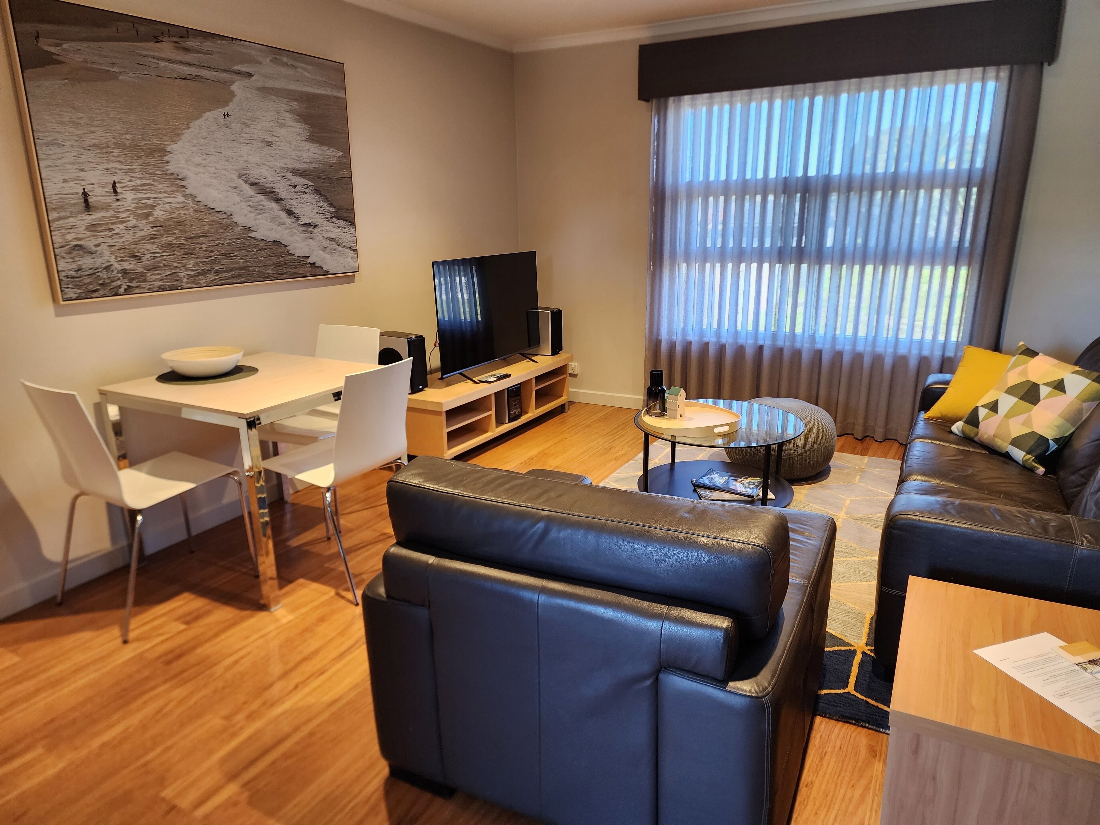 A modern living room with a dining area, a sofa, a coffee table, and a television.