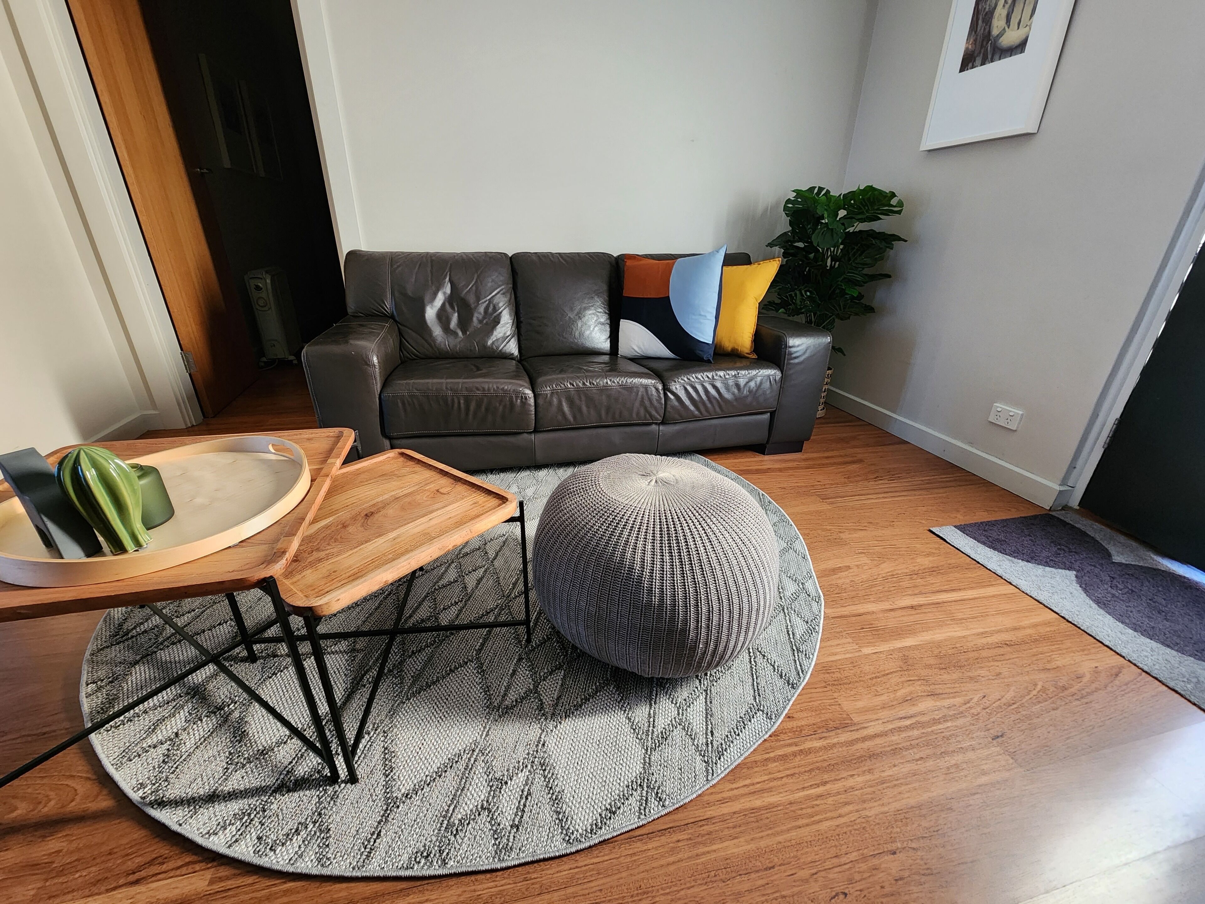 Ein Wohnzimmer mit einem Ledersofa, einem runden Teppich und einem Holztisch.