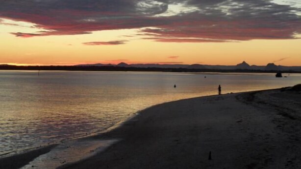 A beach with a calm sea, a clear sky, and distant mountains. - Sylvan Beach Resort (Bellara)