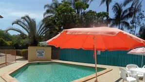 A small pool with a warning sign, surrounded by palm trees and a fenced area. - Sylvan Beach Resort (Bellara)