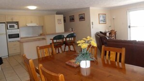 A compact living space with a dining area, kitchen, and a sofa. - Sylvan Beach Resort (Bellara)