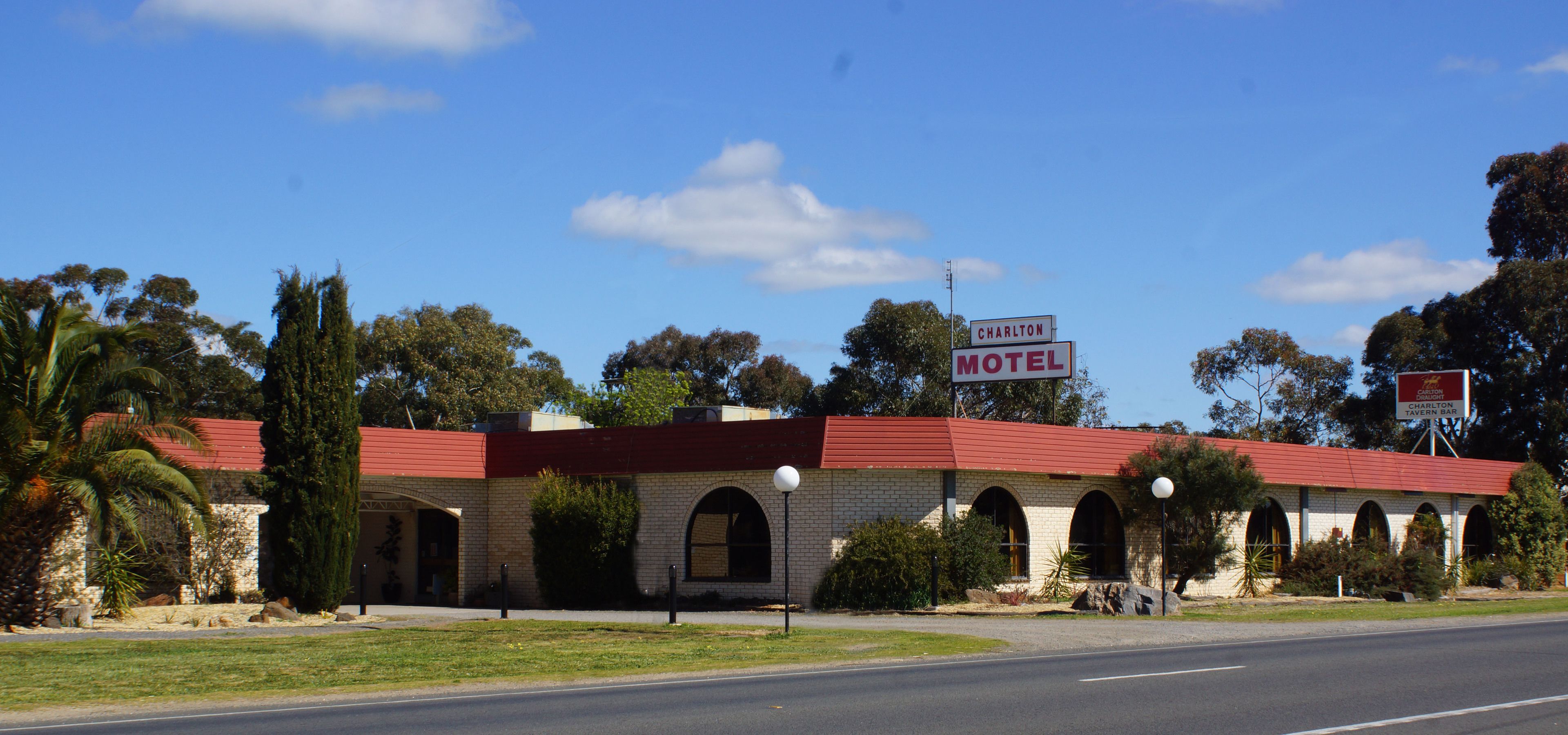 A motel with a red roof, brick walls, and arched windows.