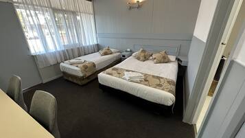 A hotel room with two beds, a small table, and a chair.