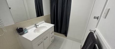 A bathroom with a white sink, a mirror, a towel rack, and a shower curtain.