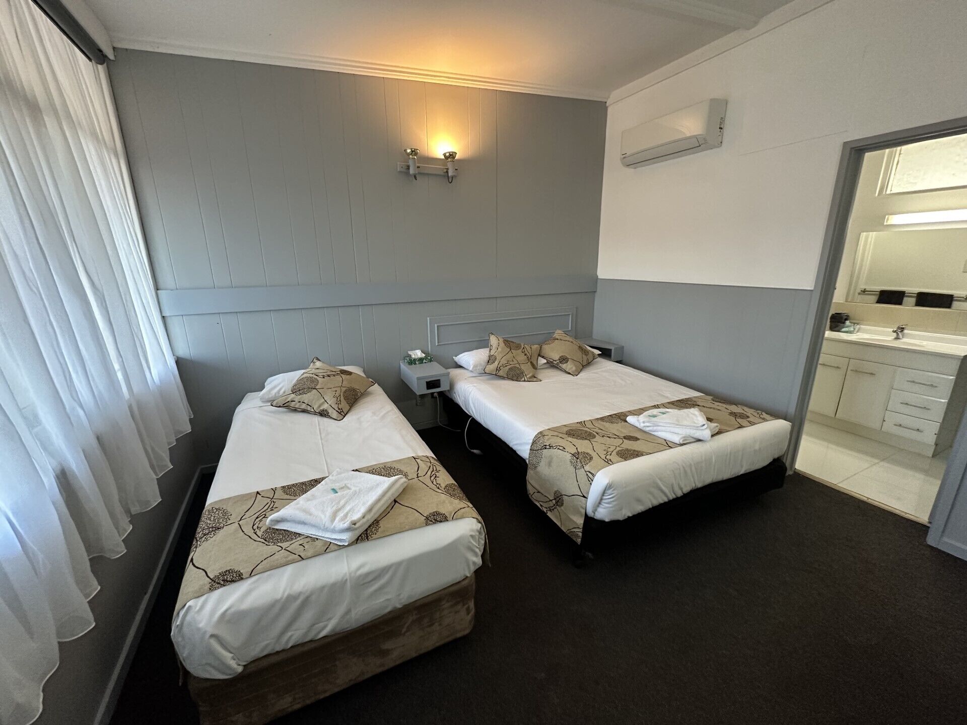 Habitación de hotel con dos camas, un baño y una pequeña zona de estar.