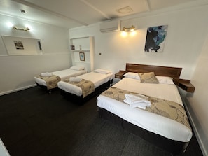 A hotel room with three single beds, a large bed, and a small table. - Charlton Motel - Victoria (Charlton)