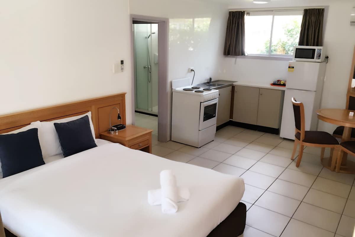 Una habitación de hotel con cama, kitchenette, ducha y comedor.