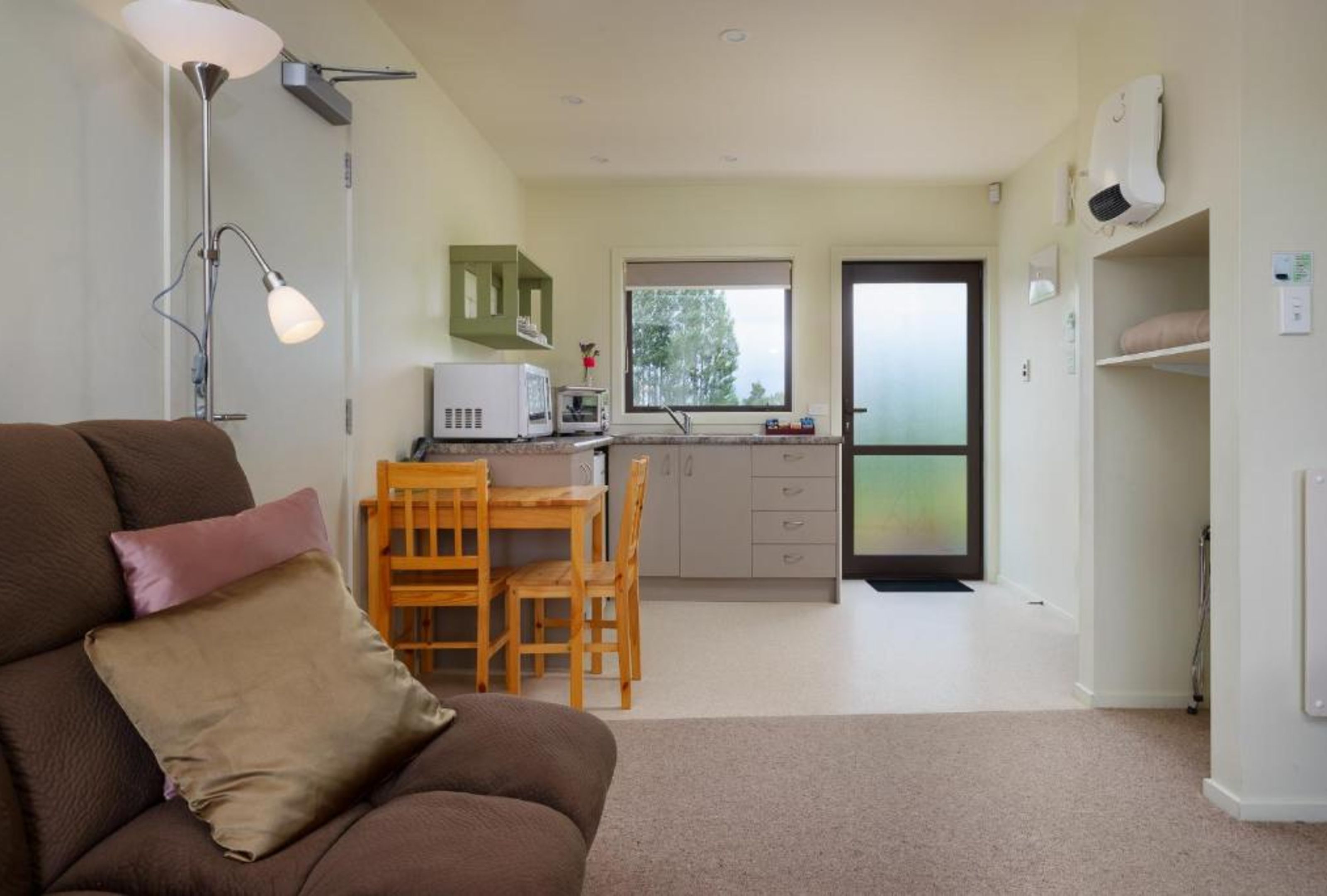 Un espacio habitable compacto con sofá, mesa de comedor y una zona de kitchenette.
