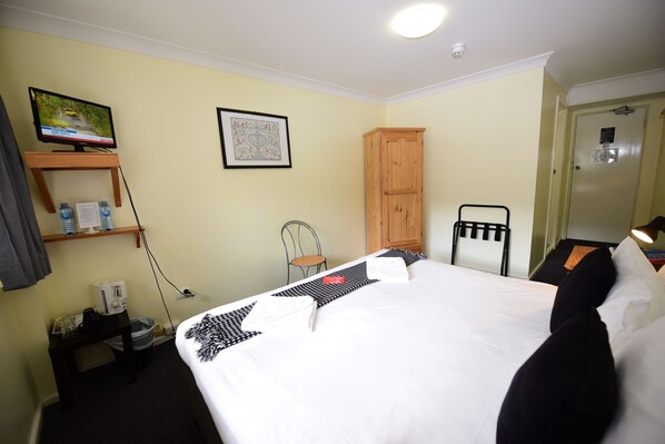 A hotel room with a bed, a television, a cabinet, a chair, and a desk with a coffee maker. - Black Bear Inn (Thredbo)