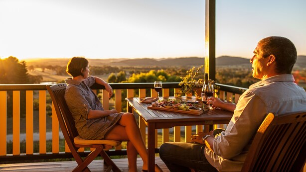 Un couple dînant sur une terrasse en bois, avec une vue magnifique.