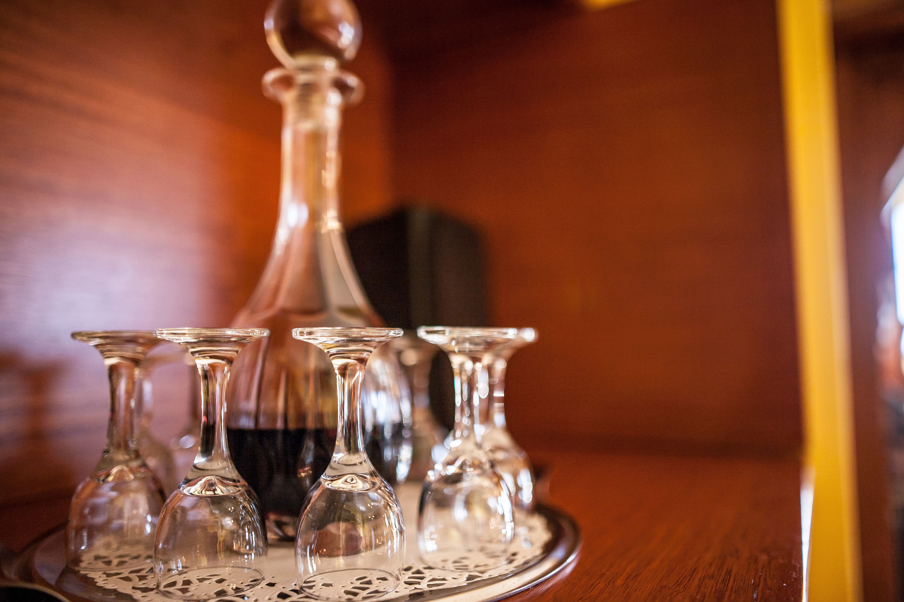 A tray with several clear wine glasses and a decanter on a wooden table.