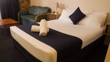 A hotel room with a bed, a chair, a nightstand, and a lamp.