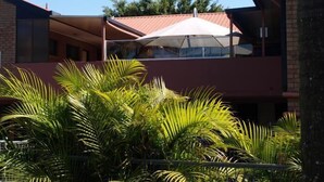A modern building with a red roof and a covered outdoor area. - Lancaster Court Motel (Annerley)