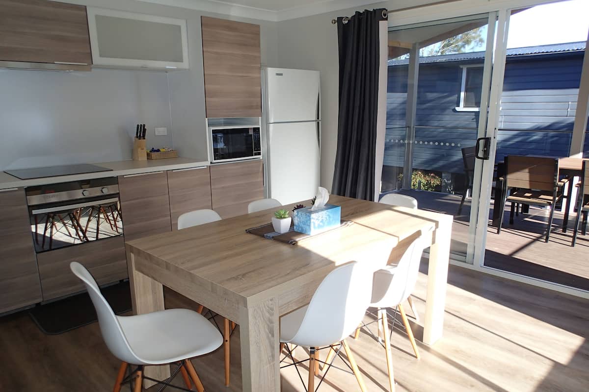 Eine moderne Küche mit einem Holztisch und weißen Stühlen, inklusive eingebautem Backofen und Kühlschrank.