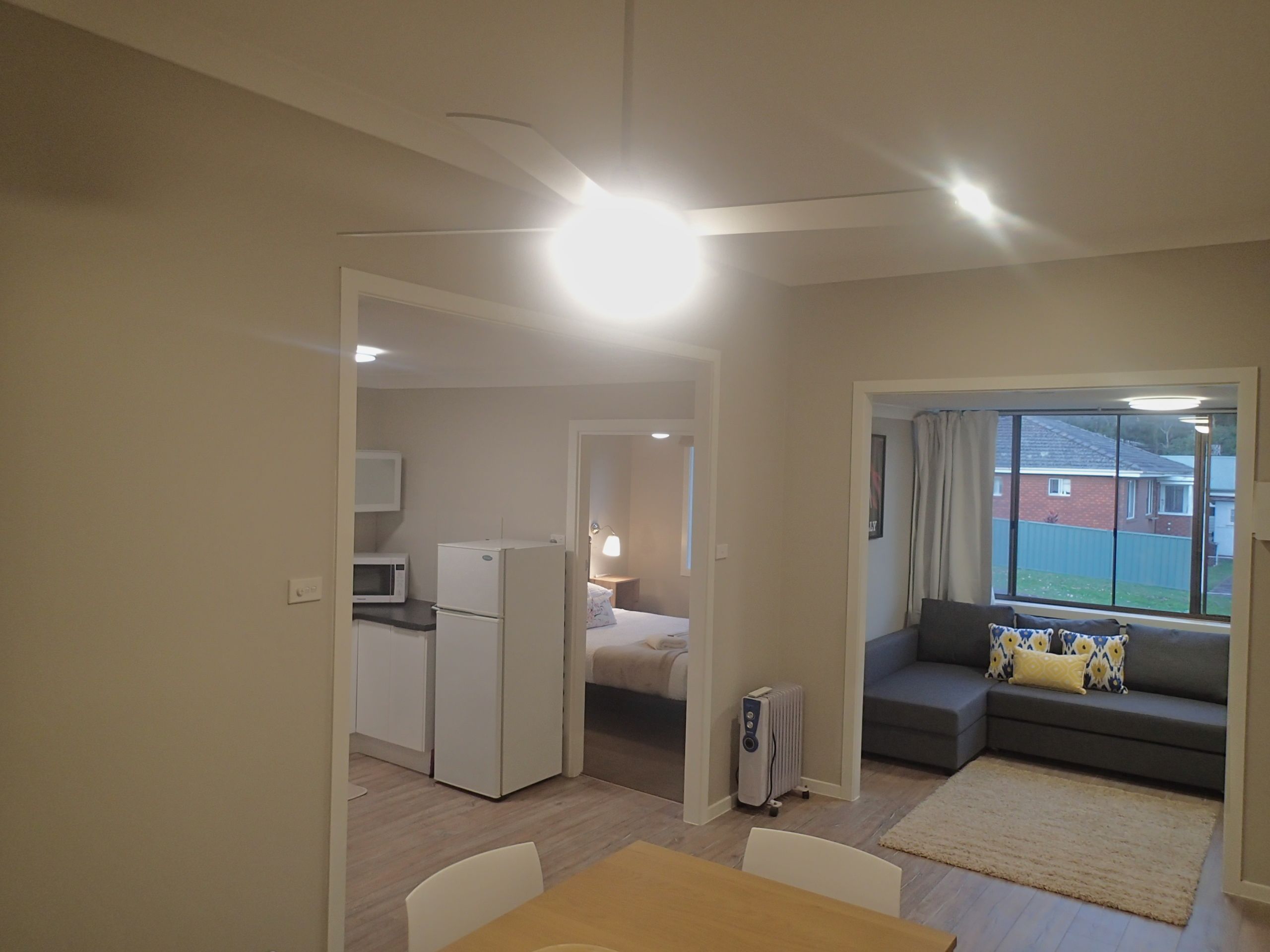A compact living space with a kitchenette, a dining area, a sofa, and a view of the outside.