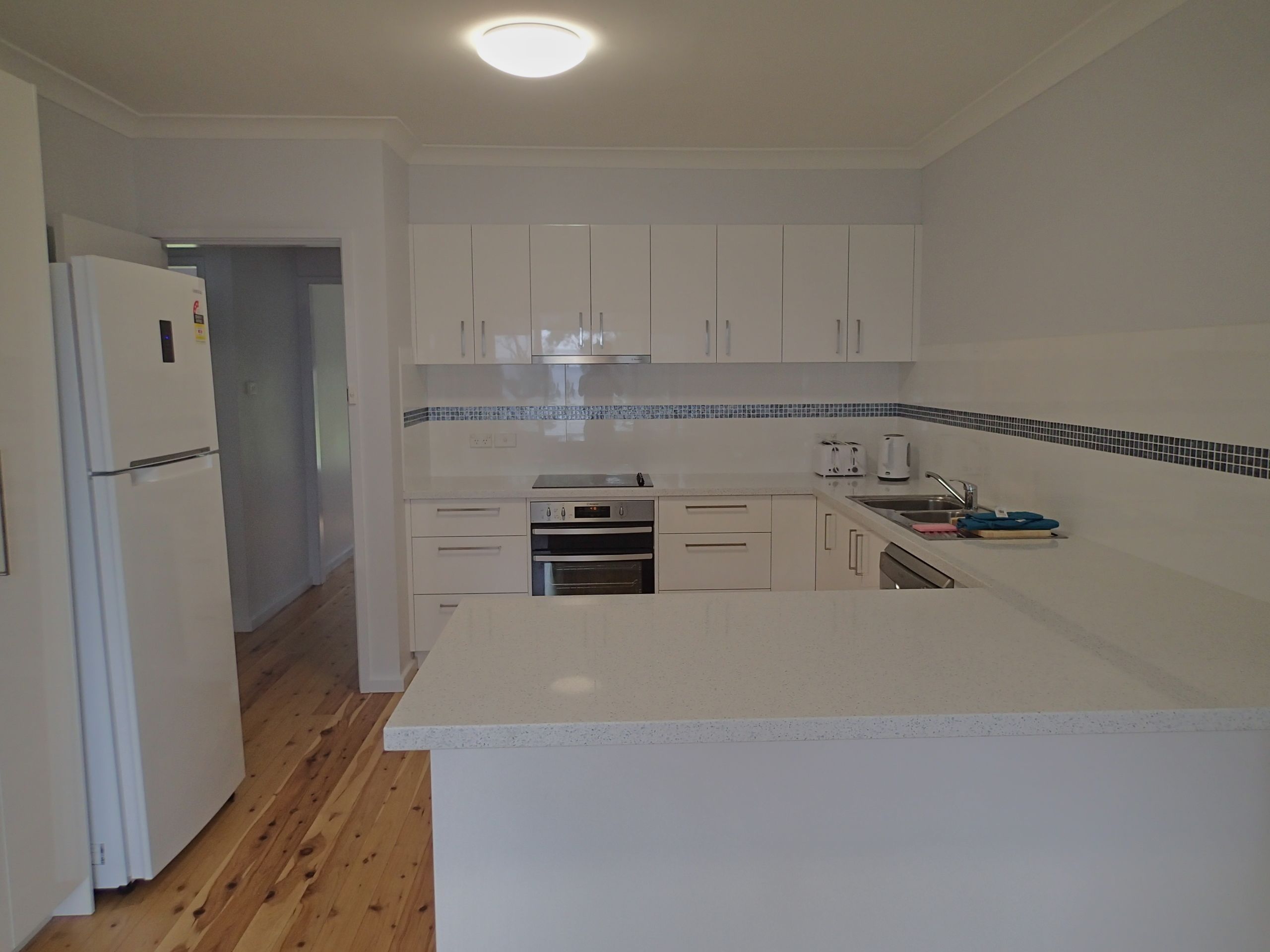 A kitchen with white cabinets, a refrigerator, an oven, and a sink.