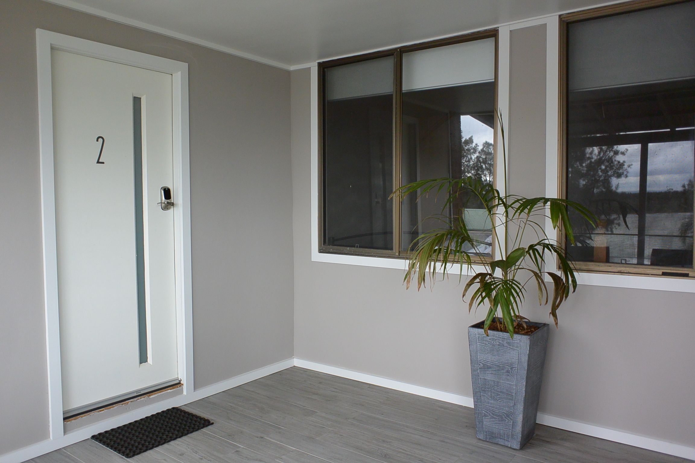 A room with a door labeled '2', a large window, and a potted plant.
