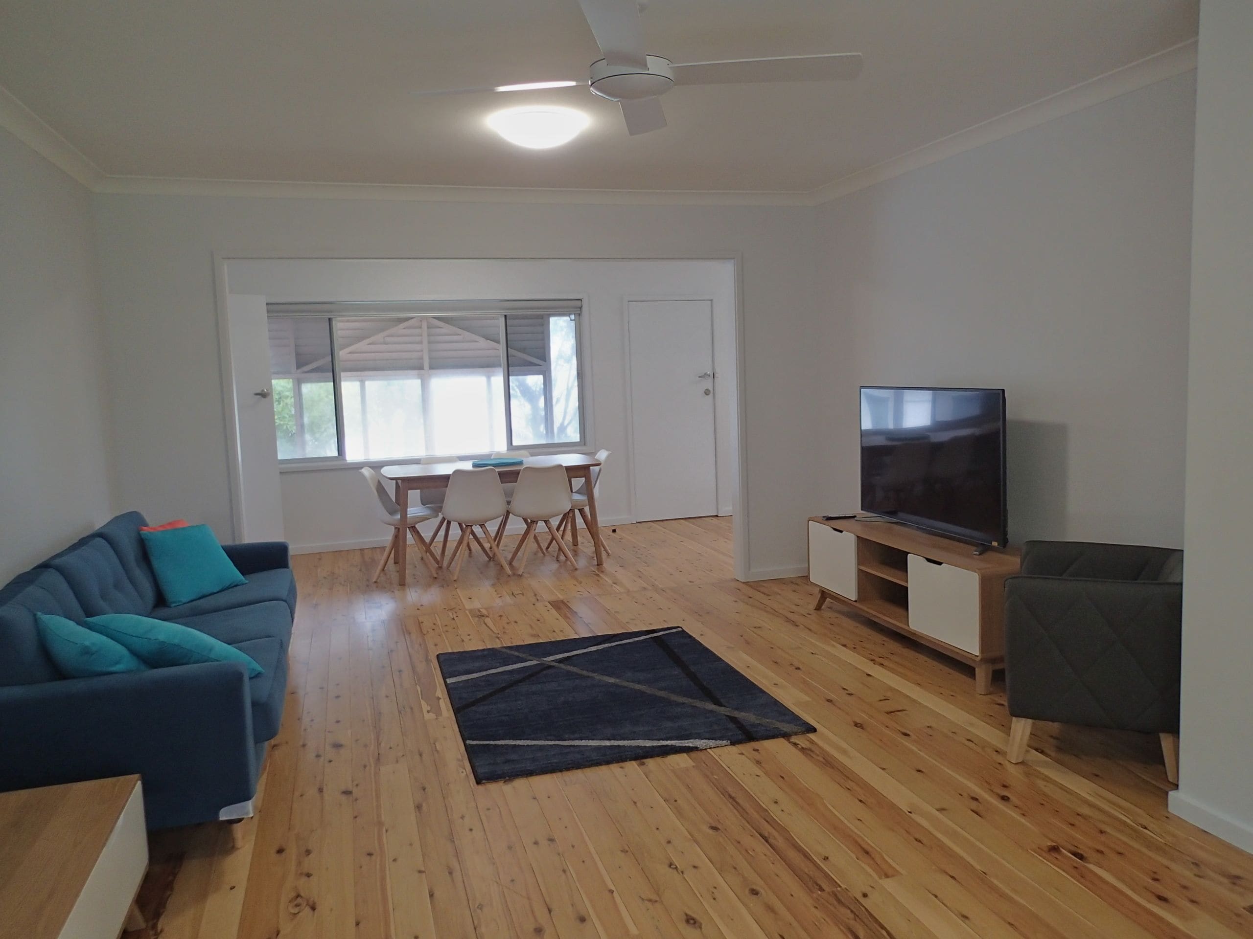 A modern living room with a sofa, TV, and dining area.