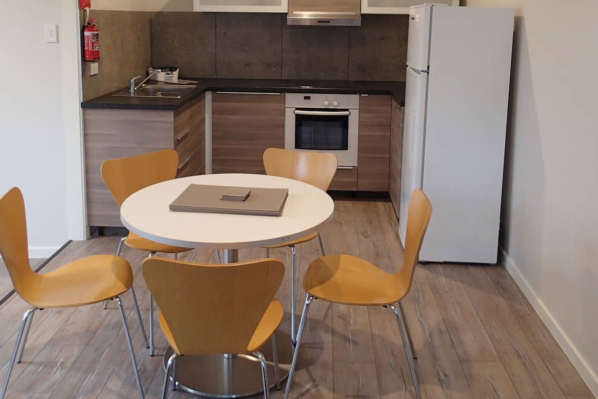 Eine kompakte Küche mit Esstisch und vier Stühlen, inklusive Backofen und Kühlschrank.