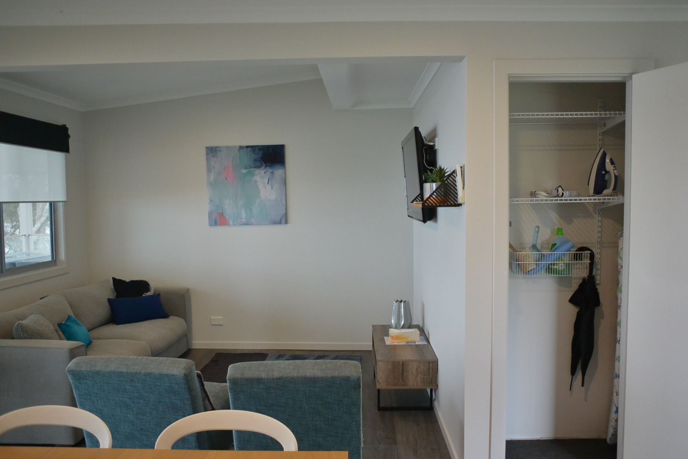 Ett modernt vardagsrum med en soffa, fåtöljer, ett soffbord, en tavla och en förvaringsmöbel med hyllor.