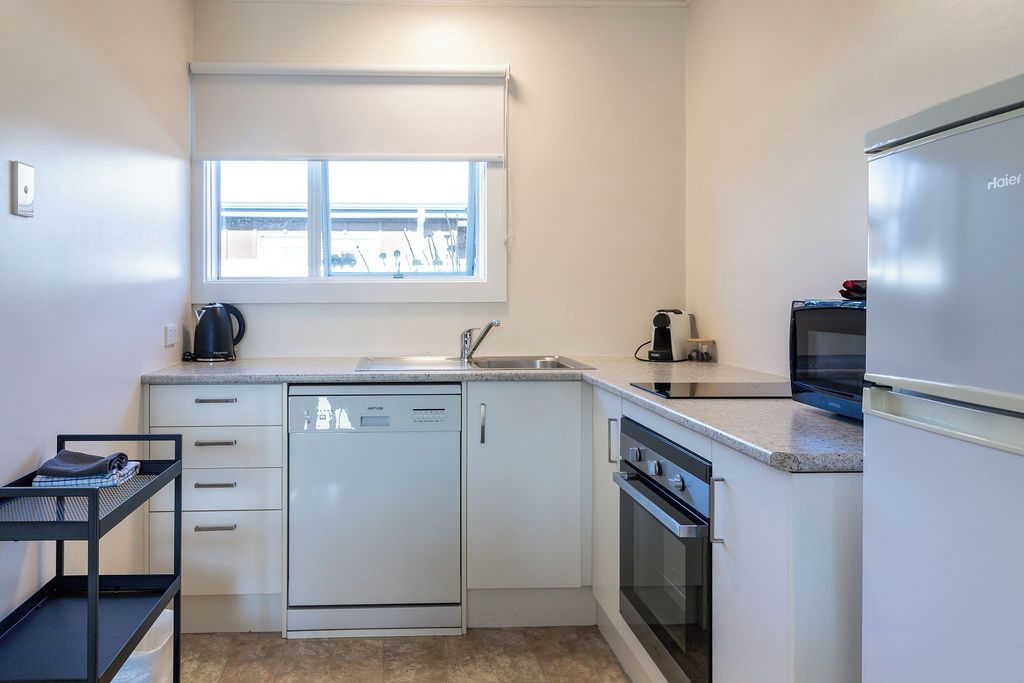 A compact kitchen with a dishwasher, oven, and a refrigerator.